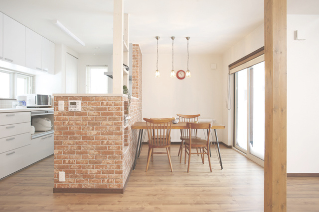 ダイニング： レンガ調の壁紙に、 デザイン違いの椅子がアクセント。