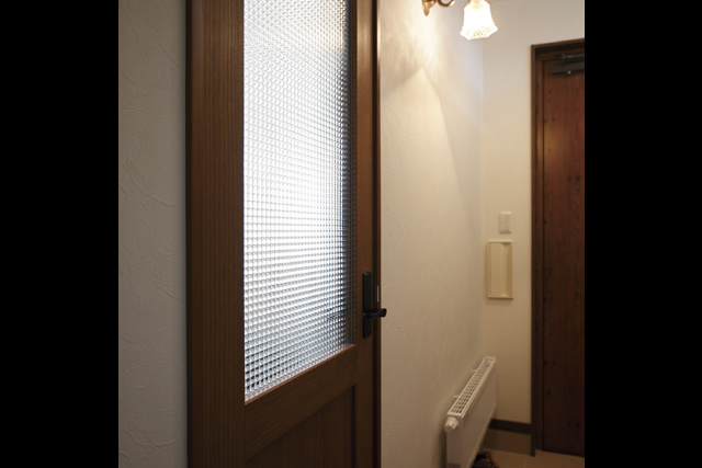 リビングドア： チェッカーガラスのリビングドアと ブラケット照明がアンティークな雰囲気を 醸すリビングの入口。