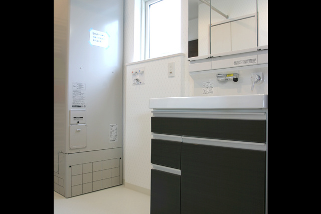 電気温水器： 電気温水器と洗面化粧台。 置き場所に困る体重計は、 化粧台下部の引出しに収納。